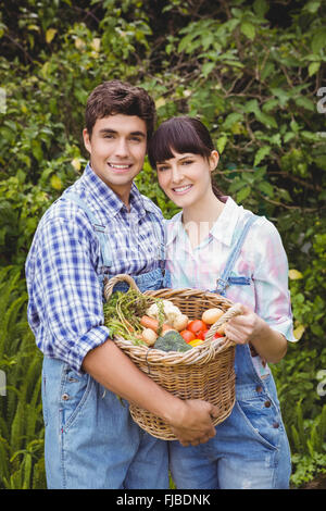 Coppia giovane tenendo un paniere di appena raccolto di ortaggi Foto Stock