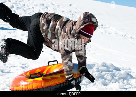 Ragazzo bello volare un tubo di neve mentre è in vacanza. Foto Stock