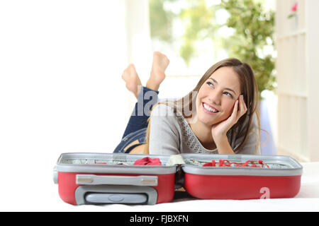 Donna felice il pensiero e la preparazione di un viaggio che giace su un letto di casa o hotel Foto Stock