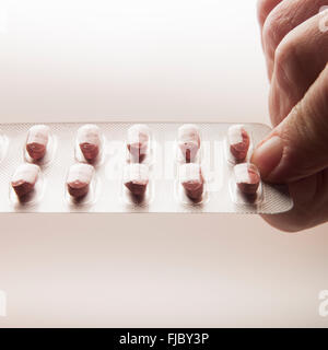 Femmina di mano azienda statine, i farmaci ipocolesterolemizzanti, nel confezionamento di blister su sfondo chiaro Foto Stock
