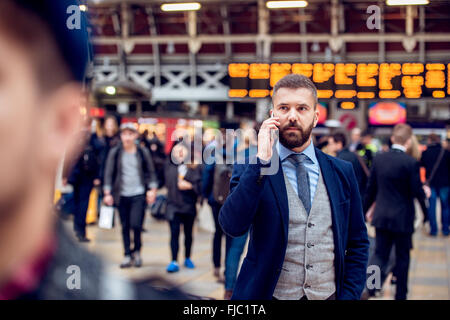 Imprenditore occupato con lo smartphone, rendendo chiamata telefonica, affollato sta Foto Stock