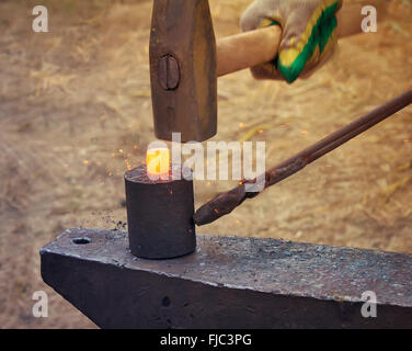 Un fabbro forgia uno sbozzato metallico sull'incudine ad una fiera in  presenza di spettatori. Fabbro medievale forge soffietto. Metallurgico di  fusione del ferro Foto stock - Alamy