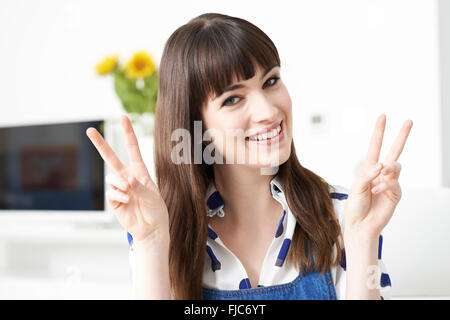 Giovane donna che fa il gesto di pace con le mani Foto Stock
