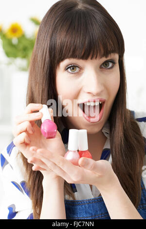 Giovane donna Azienda Bottiglie colorate di smalto per unghie Foto Stock
