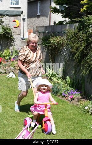 Nana & nipote avente un buon tempo, divertirsi giocando e in esecuzione nel giardino in una calda giornata d'estate in Dublino Irlanda Foto Stock