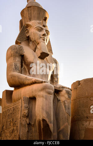 Statua di Ramessess II seduto di fronte a una delle porte del tempio di Luxor. Foto Stock