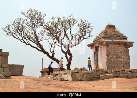 Gli uomini indù a camminare verso un piccolo tempio nelle rovine di Hampi, India Foto Stock