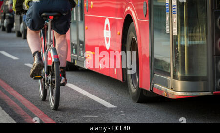 Ciclista utilizzando il Santander Noleggio Biciclette regime passa un autobus di Londra in un ciclo di una corsia di marcia Foto Stock