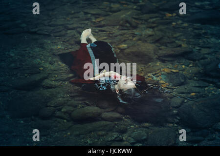 Bella donna di galleggiamento in acqua scura . Ofelia concettuale Foto Stock