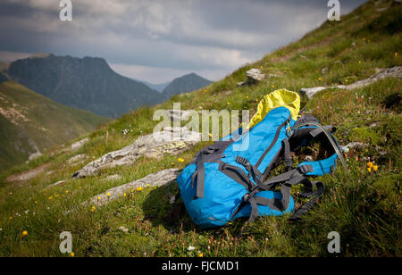 Zaino o zaino equilibrata contro una roccia sulla sommità della cima di una montagna Foto Stock