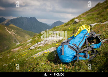 Zaino o zaino equilibrata contro una roccia sulla sommità della cima di una montagna Foto Stock