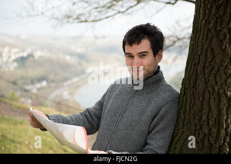 Giovane uomo di fronte a Rheine river, Germania, usando la mappa Foto Stock