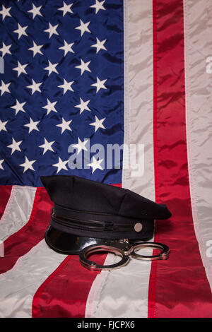 Un cappello di polizia con le manette su una bandiera americana sfondo. Foto Stock