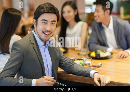 Giovane uomo cinese a cena con gli amici Foto Stock