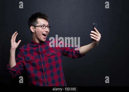 Emozionato uomo cinese tenendo un telefono intelligente Foto Stock