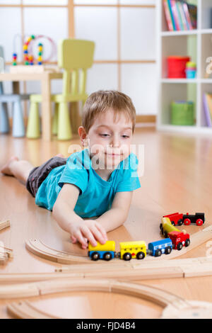 Bambino ragazzo giocando con la ferrovia di legno sul pavimento Foto Stock