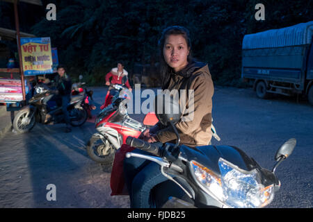 Una giovane donna riposa sulla sua moto nel villaggio di Ban Khoang nel nord del Vietnam Foto Stock
