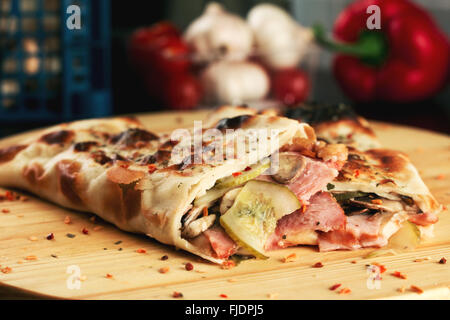 Calzone di rotoli di pizza con prosciutto e funghi. Profondità di campo Foto Stock