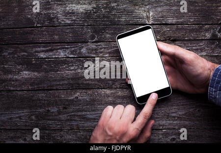 Mani maschili in camicia toccando svuota lo schermo dello smartphone su scuro legno rustico con copia spazio. Al di sopra di vista lay piatto Foto Stock