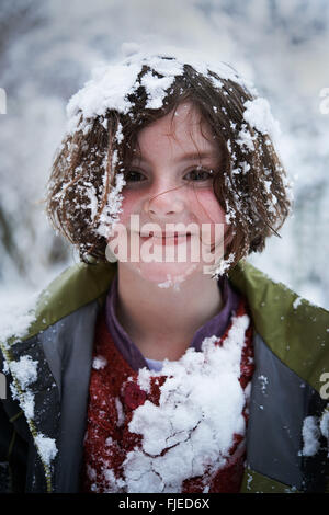 Un bambino coperto di neve,snow attaccarsi ai suoi vestiti e capelli Foto Stock