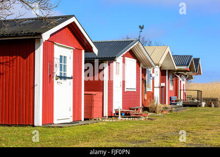 Solvesborg, Svezia - 27 Febbraio 2016: una fila di rosso, in legno cabine di pesca ora utilizzato come vacanza costiera cabine. Foto Stock