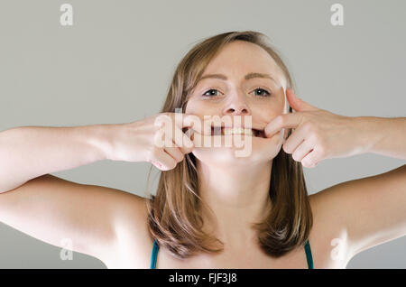 Giovane donna tirando una divertente volto Foto Stock