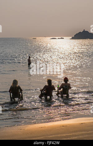 Backpackers avente una birra al tramonto sulla spiaggia di Om, Gokarna nello stato indiano di Karnataka Foto Stock