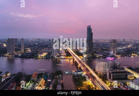 Trasporto di Bangkok al tramonto con il moderno edificio aziendale lungo il fiume (Thailandia) Foto Stock