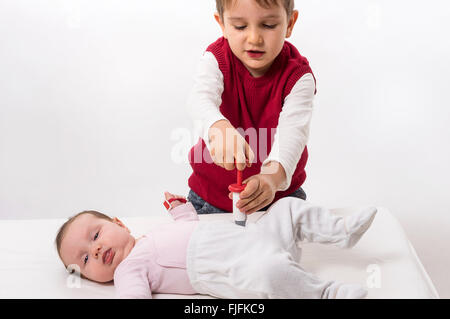 Fratello di pagare come medico e paziente con il suo bambino sorella. Il ragazzo rende l'iniezione con siringa. Foto Stock