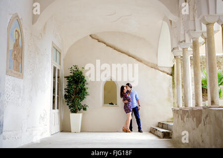 Un giovane in amore bruna giovane appoggiato nell'impostazione di una bella, vecchio edificio Mediterraneo a Costiera Amalfitana, Italia, Foto Stock