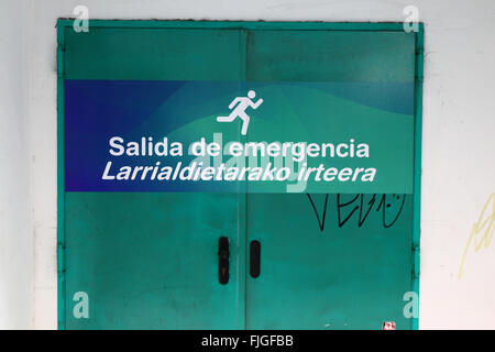 Uscita di emergenza scritta sulla porta sia in spagnolo e basco lingue, Bilbao, Paesi Baschi Foto Stock