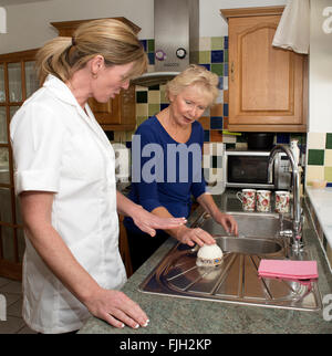 Un caregiver a lavorare con un cliente con il cliente nella sua cucina durante una visita a casa Foto Stock