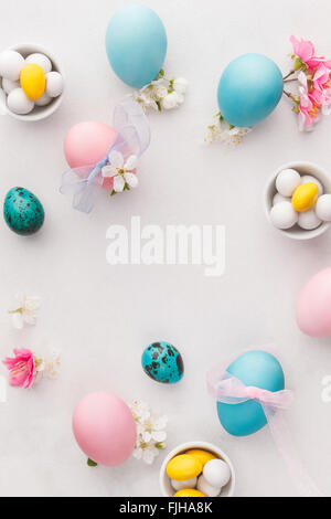 Uova di Pasqua. Vari colori pastello uova di Pasqua, caramelle e decorazioni. Macro, il fuoco selettivo, vista dall'alto, uno spazio vuoto Foto Stock