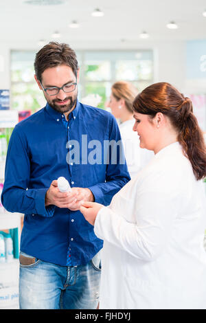 Il farmacista o drug store sales donna consigliare il cliente sui prodotti per la cura per gli uomini Foto Stock