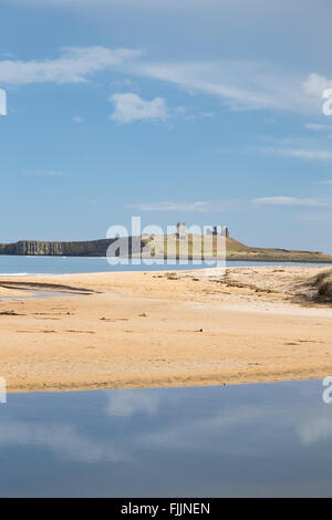 Il castello di Dunstanburgh attraverso Embleton Bay sulla costa nord est di Northumberland, England, Regno Unito Foto Stock