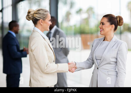 Due belle handshaking imprenditrici in office Foto Stock