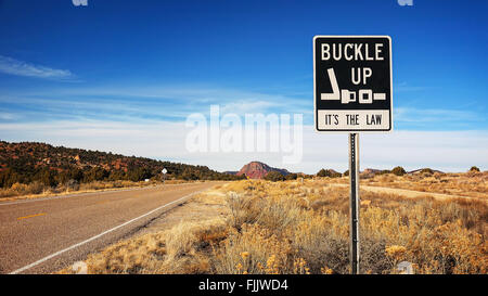 La fibbia fino è la legge segno lungo un'autostrada Arizona Foto Stock