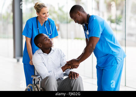 Amichevole maschio medico lo handshaking con pazienti portatori di handicap Foto Stock