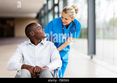 Premurosa infermiera femmina parlando al paziente disabile in ospedale Foto Stock