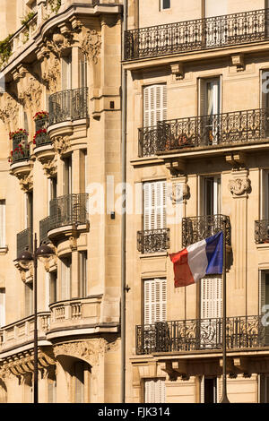 Dettaglio del tipico Hausmann-ser appartamento edificio con bandiera francese a Parigi, Francia Foto Stock