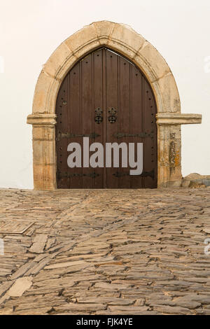 Portale ad arco e strada di ciottoli nel villaggio storico di Monsaraz, regione Alentejo, Portogallo. Architettura medievale siti di viaggio. Foto Stock