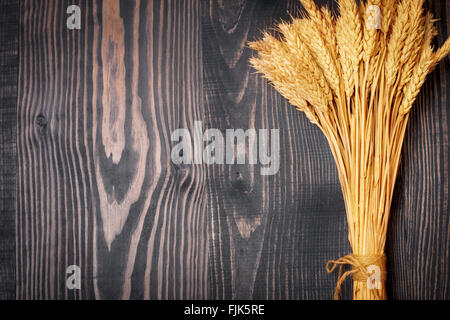 Luminose mature spighe di grano al buio su un sfondo di legno Foto Stock