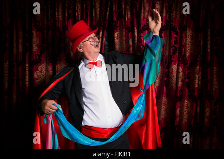 Funny senior mago comico fare trucchi di magia sul palco Foto Stock