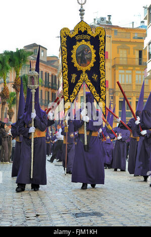 Processioni di Nazarenos a camminare per le strade di notte durante la Semana Santa di Malaga, in Spagna. Foto Stock