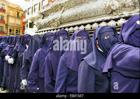 Processioni di Nazarenos a camminare per le strade di notte durante la Semana Santa di Malaga, in Spagna. Foto Stock