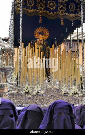 Un gruppo di incappucciati portatori (chiamato Costaleros) portante un galleggiante religiosa (noto come Tronos) nelle processioni tenutasi a Malaga Foto Stock
