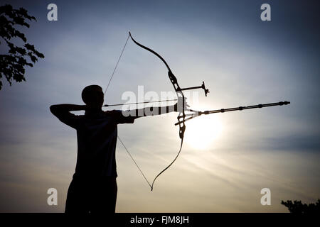 Immagine iconica di un arciere sparando una freccia con un inchino, Foto Stock