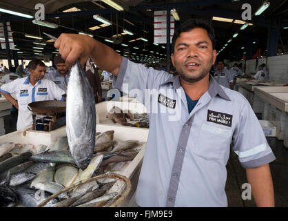 Mercato del Pesce lavoratore tenendo un pesce in vendita a Dubai il mercato del pesce in Deira Emirati Arabi Uniti Foto Stock