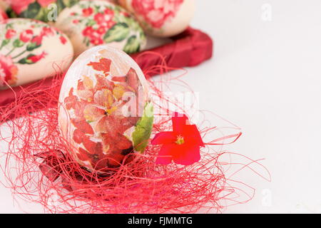 Decoupage decorato uovo di Pasqua sulla paglia rosso Foto Stock