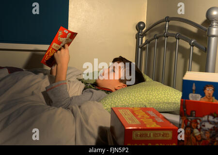 Ragazzo lettura a letto bambino la lettura di un libro che giace nel suo letto, Bedtime Story, di coricarsi leggere Foto Stock